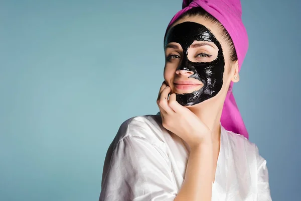 Lány a fején egy törülközővel alkalmazott tisztító maszk arcán fekete — Stock Fotó