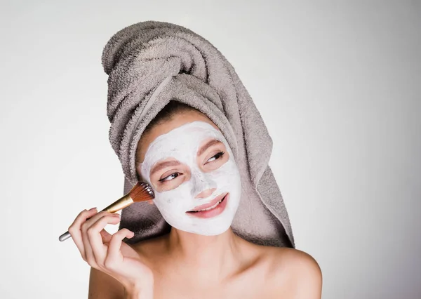 Девушка с полотенцем на голове надела очищающую маску на лицо — стоковое фото