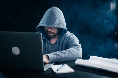 Bir dizüstü bilgisayar bir başlıklı arkasında çalışan bir genç hacker