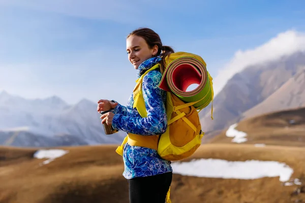 Menina feliz em uma jaqueta azul viaja através das montanhas caucasianas com uma mochila — Fotografia de Stock