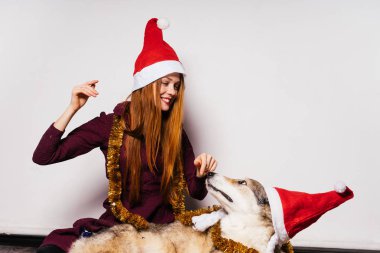 mutlu Noel Baba gibi kırmızı bere Kızıl saçlı kız köpeğiyle yeni yıl kutluyor