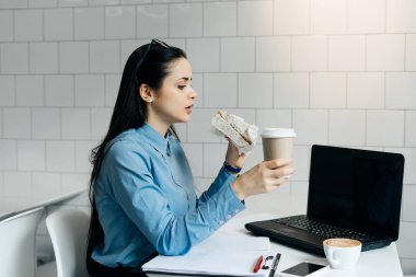 mavi gömlekli sandviç ve kahve ile kahve dükkanında Öğle Yemeği aç genç kız