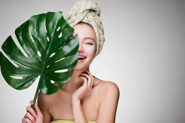 Kafasındaki bir yaprak yeşil gözleri yamalar, spa prosedürleri altında tutan genç kız bir havlu ile gülüyor