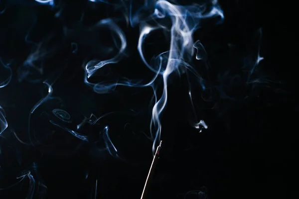 Тлеющая ароматическая палка в темноте, много синего дыма — стоковое фото