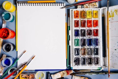 Masanın üzerine orada parlak suluboya ve sanat guaş, birçok fırçalar ve kurşun kalemler, beyaz kağıt çizim için
