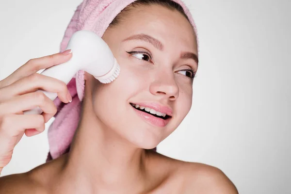 Giovane ragazza su bianco sorridente purifica la sua pelle del viso — Foto Stock