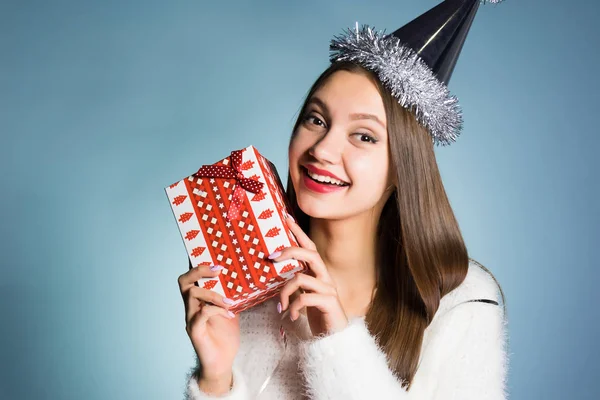 Счастливая девушка в праздничной кепке с подарком в руках — стоковое фото