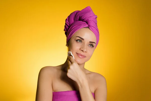 Κορίτσι με μια πετσέτα στο κεφάλι της σβήνοντας ένα make-up με ένα δίσκο βαμβακιού — Φωτογραφία Αρχείου