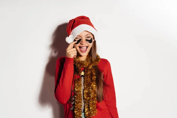 La muchacha feliz en el traje de Año Nuevo ha puesto bajo los ojos la máscara hidrogel —  Fotos de Stock