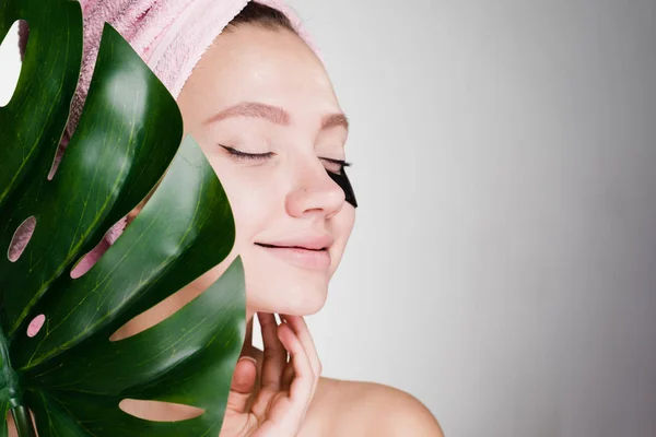 Happy girl with a towel on her head and a big leaf in her hands — Stock Photo, Image