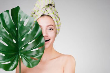 bir havlu ile genç kız başını tutan bir yaprak yeşil, gün spa gülüyor