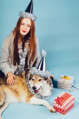 Kafasındaki bir kap ile sevimli bir kızıl saçlı kız yere köpeğiyle oturuyor, bir yeni yıl ve Noel kutluyor