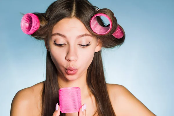 Divertida joven hace un peinado elegante con la ayuda de grandes rizadores de color rosa —  Fotos de Stock