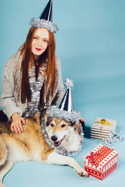 一个可爱的 red-haired 女孩头上戴着帽子, 和她的狗一起坐在地板上, 庆祝新年和圣诞节。 — 图库照片