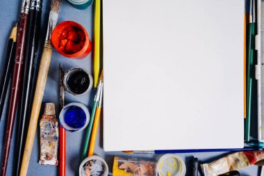 mavi bir tabloda sanat malzemeleri yatıyordu, kağıt ve parlak renkli boyalar beyaz