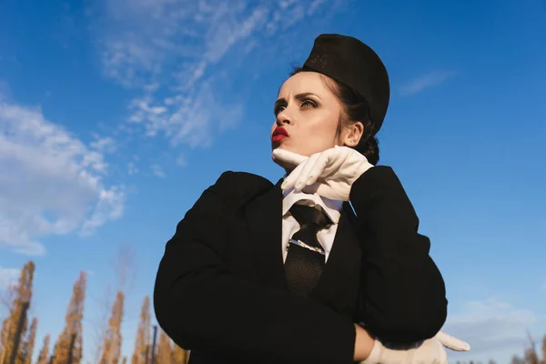 Divertente giovane hostess donna in uniforme sotto un cielo blu, pensando di aeroplani — Foto Stock