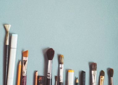 sanatsal fırçaların, kalemler ve işaretleyiciler mavi bir masada yalan