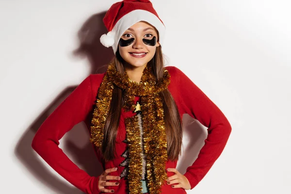 Ευτυχισμένος χαμογελαστό κορίτσι σε ρούχα Χριστούγεννα γιορτάζει τα Χριστούγεννα, κάτω από τα μάτια μαύρα μπαλώματα — Φωτογραφία Αρχείου