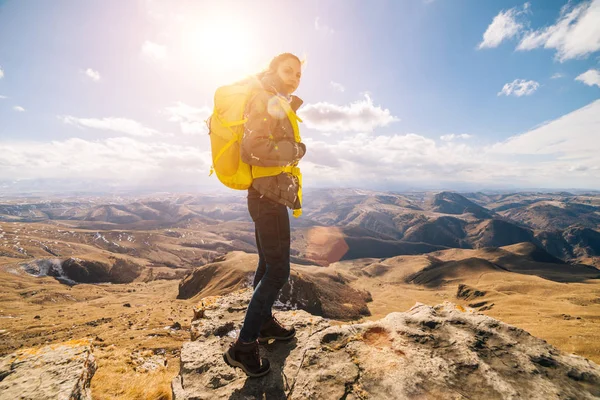 Joven activa con una mochila amarilla viaja a través de las montañas del Cáucaso al sol —  Fotos de Stock