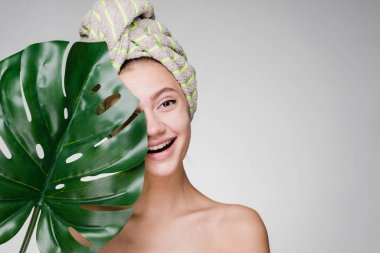 yeşil yaprak tutan bir spa zevk mutlu gülümseyen kız başında, bir havlu ile