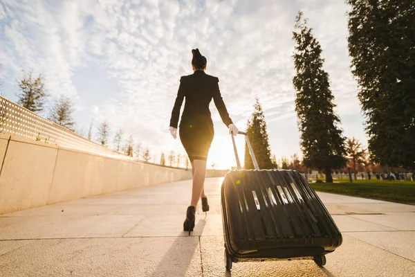 A slender young woman of a stewardess in uniform with a suitcase goes on a flight — Stock Photo, Image