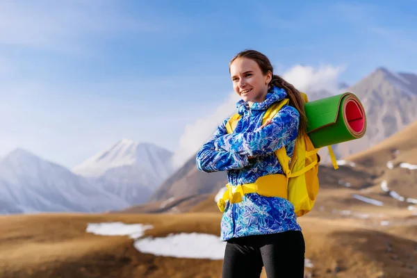 Szczęśliwa młoda dziewczyna w Błękitnej Kurtki przemieszcza się przez góry Kaukazu z plecaka i namiot — Zdjęcie stockowe