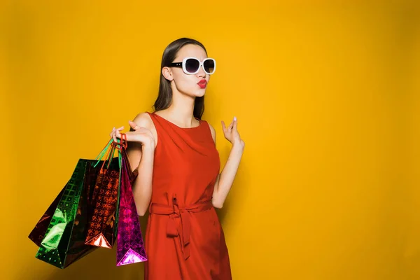 Stijlvolle jong meisje shopaholic in rode jurk en zonnebril houdt zwarte vrijdag — Stockfoto