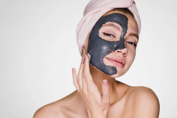 Μια ελκυστική νεαρή κοπέλα έχει βάλει ένα χρήσιμο άργιλος μάσκα στο πρόσωπό της, απολαμβάνοντας το σπα — Φωτογραφία Αρχείου