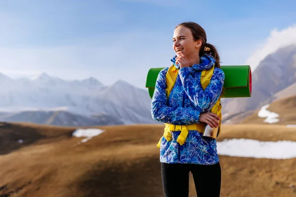 Feliz chica activa en una chaqueta azul viaja a lo largo de la cresta del Cáucaso con una mochila —  Fotos de Stock