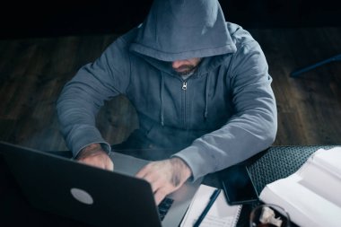 adam hacker bir kukuleta ile bir kazak'ı bir dizüstü oturur