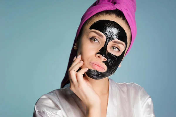 Nő a fején egy törülközővel alkalmazd a tisztító fekete maszkot arcán — Stock Fotó