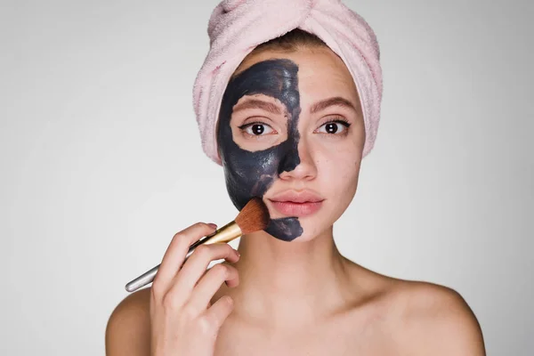 Mujer con una toalla en la cabeza aplicar una máscara negra limpiadora en la cara — Foto de Stock