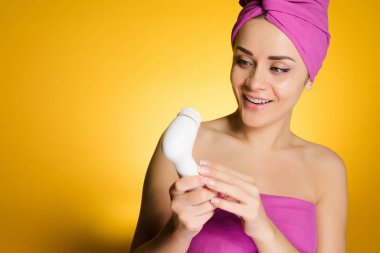 mutlu kadın başında bir havlu ile elektrikli bir fırça elinde tutar.