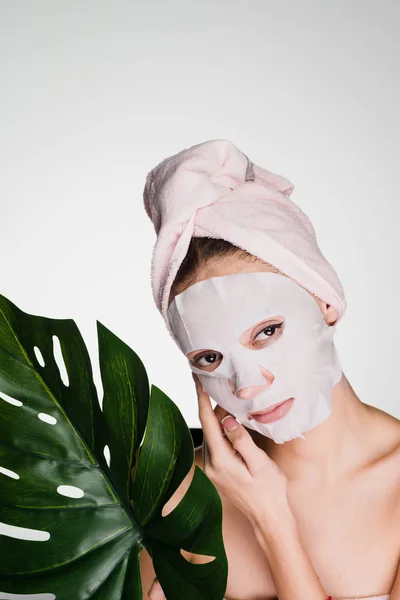 Woman with a towel on her head apply a cleansing mask on her face — Stock Photo, Image