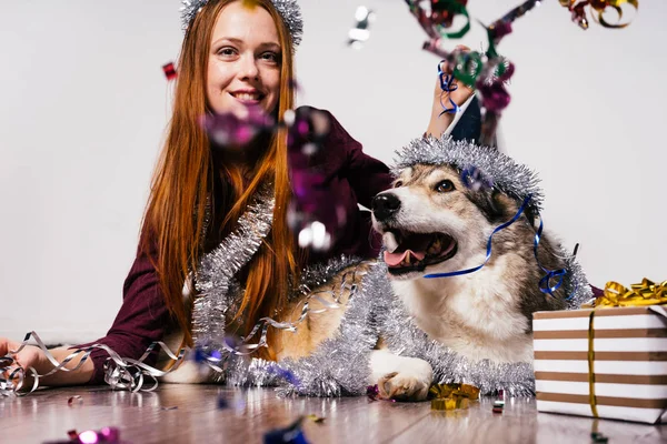 Happy woman in a Christmas hat sits next to a dog — Stock Photo, Image