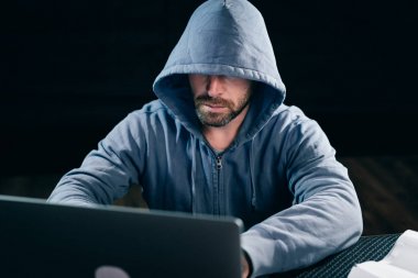 Bir hacker bir kapüşonlu sweatshirt ' bir dizüstü oturur