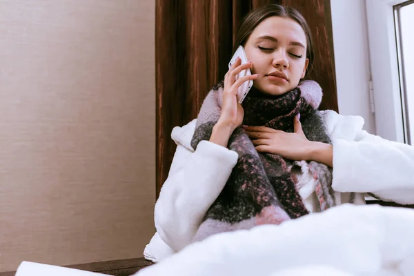 Una mujer fría con una gran bufanda caliente hablando por teléfono — Foto de Stock