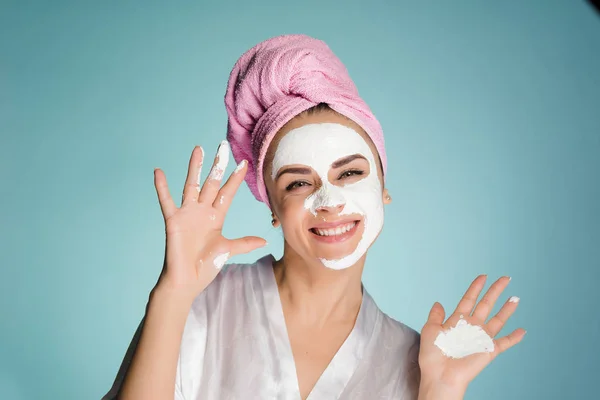 Femme heureuse avec une serviette sur la tête applique un masque nettoyant sur son visage — Photo