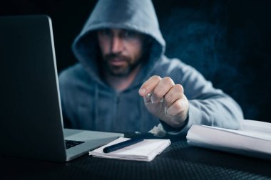 bir adam hacker bir dizüstü bilgisayar çalışır ve bir defter için ulaşır