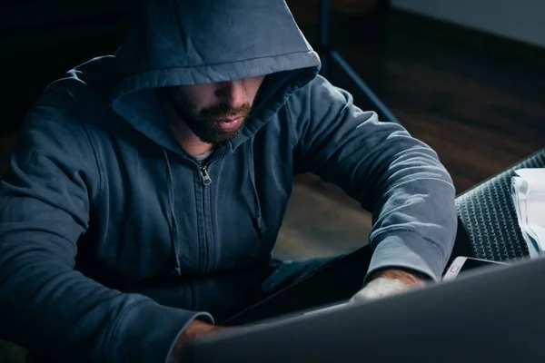 Hacker im Anzug mit Kapuze sitzt am Laptop — Stockfoto