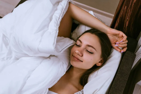 En kvinna sover i sängen under en filt — Stockfoto