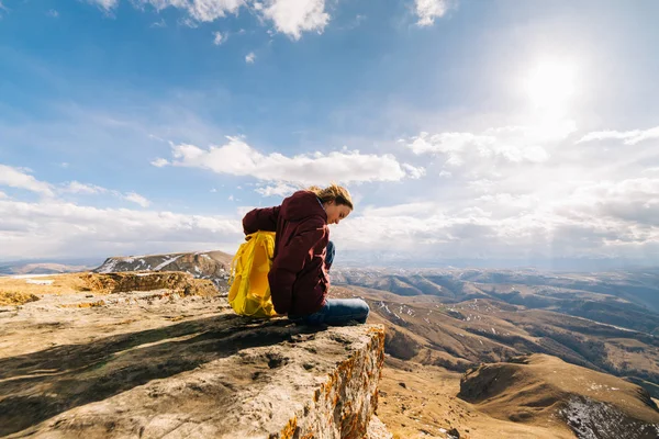 Turista mujer con una mochila sobre un fondo de altas montañas —  Fotos de Stock