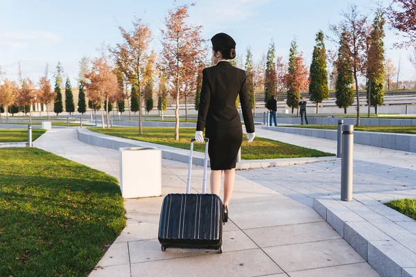 Nő a repülés stewardess hordoz egy nagy bőröndöt — Stock Fotó