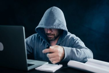 adam hacker diz üstü başlıklı arkasına oturur