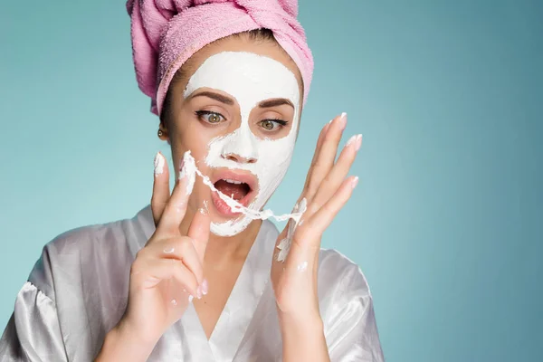 Kobieta z ręcznikiem na głowie usuwa białe maski z twarzy — Zdjęcie stockowe