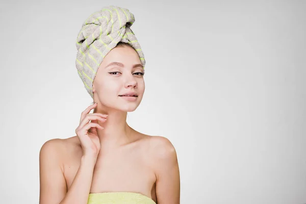 Γυναίκα με μια πετσέτα στο κεφάλι της σε ένα γκρίζο φόντο — Φωτογραφία Αρχείου