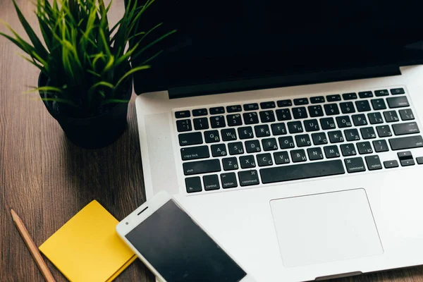 Op een houten tafel is een laptop en telefoon — Stockfoto