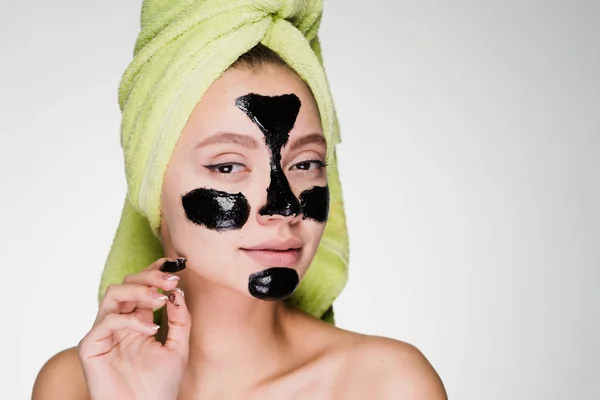 Woman with a towel on her head on a white background with a black mask on her face — Stock Photo, Image