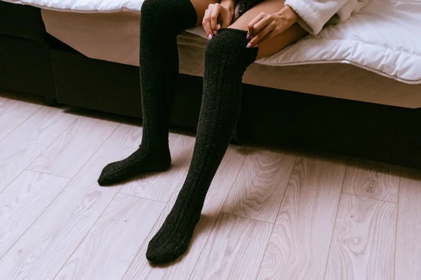 Nő ült az ágyra, és öltözködés harisnya a lába — Stock Fotó