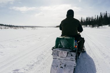 bir adam sıcak giysiler içinde bir karla kaplı alanda biniyor